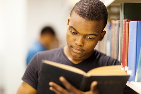 Photo of a teen reading a book in a library